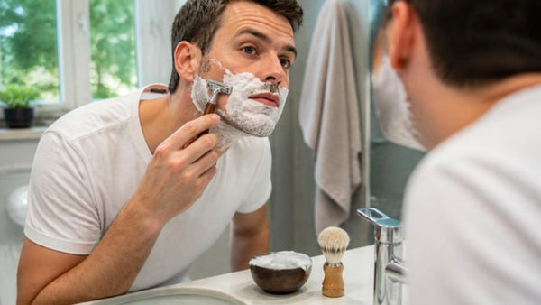 Homme barbu qui apprend comment utiliser un rasoir de sûreté devant le miroir de la salle de bain