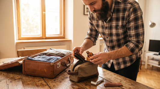 Homme barbu qui prépare son kit barbe de voyage dans une trousse à côté de sa valise