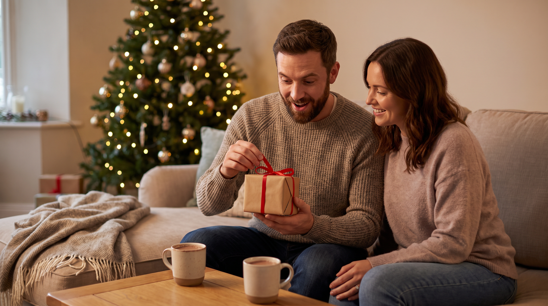 Cadeau de Noël pour son mari : un homme barbu ouvre un cadeau à côté de sa femme devant le sapin