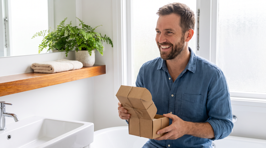 Cadeau original et pratique pour homme : un homme barbu ouvre un petit cadeau dans une salle de bain propre