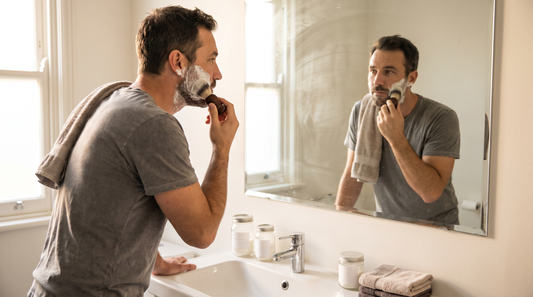 Comment bien se raser : un homme applique de la mousse à raser au blaireau devant le miroir